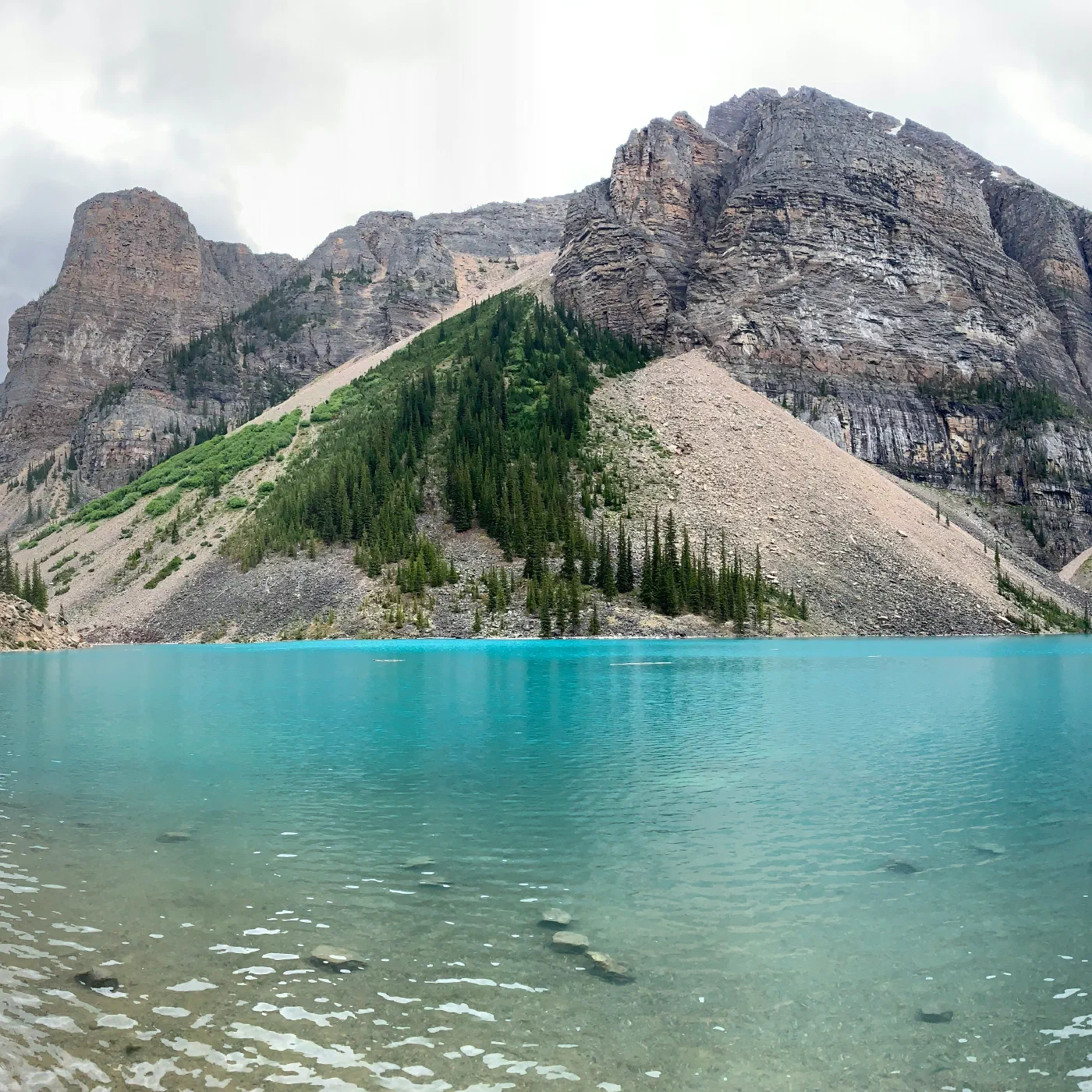 Turquoise glacial lake ringed by jagged mountains, with canoes moored at a dock